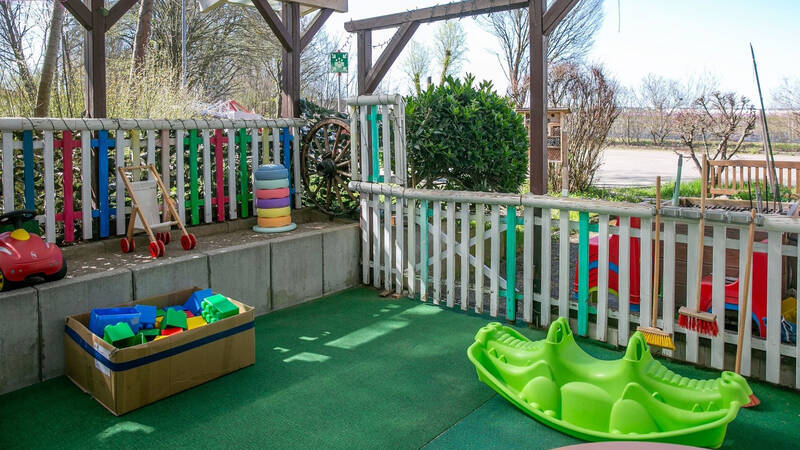 Ein fröhlich bunter Spielbereich im Außenbereich mit Spielgeräten für die Kleinsten